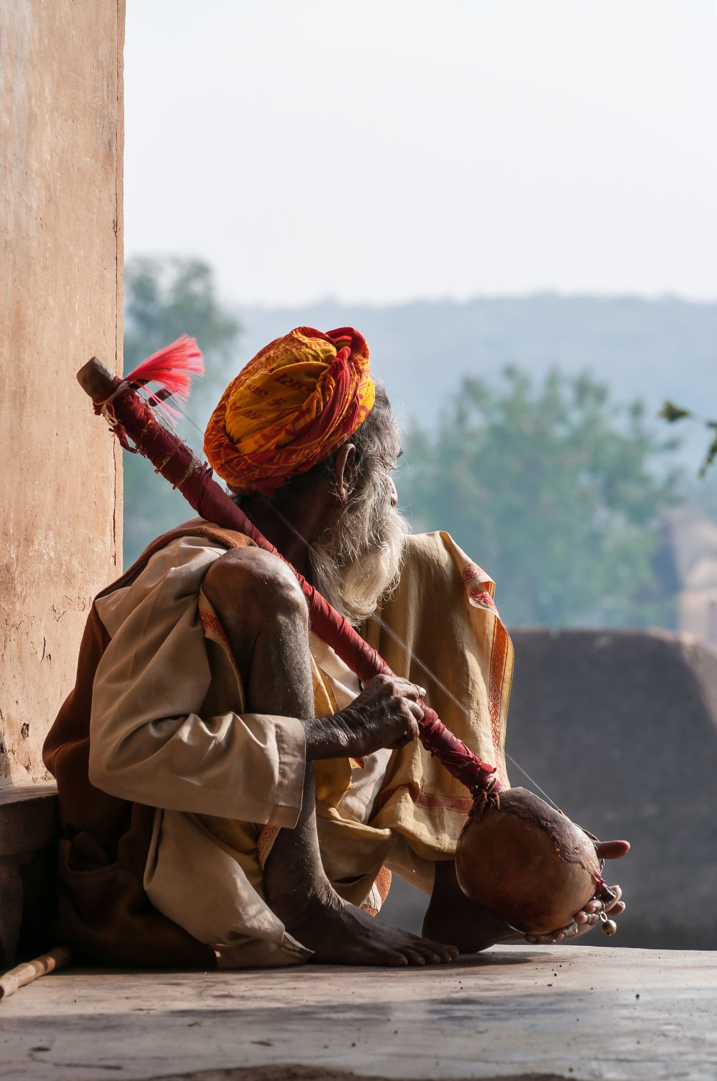 An unidentified Indian sadhu playing tumbi near the window of the Chaturbhuj Temple in Orchha, Madhya Pradesh. The tumbi is an ancient musical instrument in India which originates from the state of Punjab 