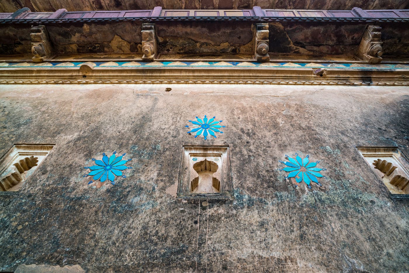 Floral inlays done in vivid blue tiles decorate a wall painting, Orchha 