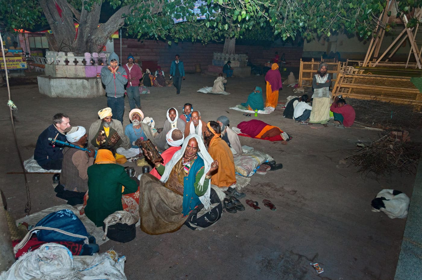 Group of Sadhus in Orchha sitting on the ground, playing musical instruments at night, and enjoying 