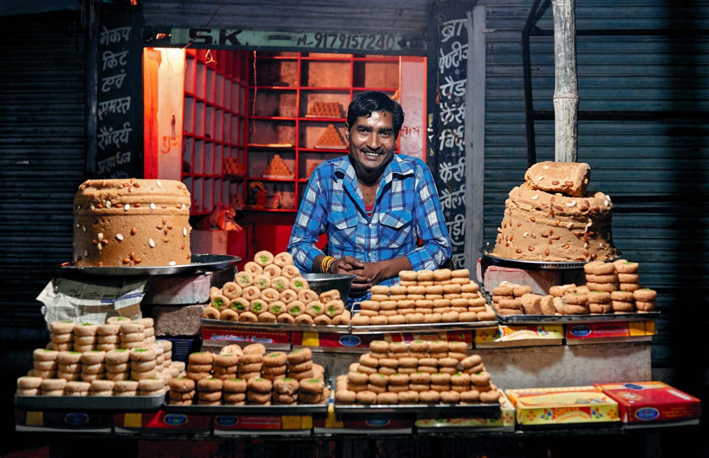 Indian man at market of Orchha selling sweets (barfi) made fom milk 