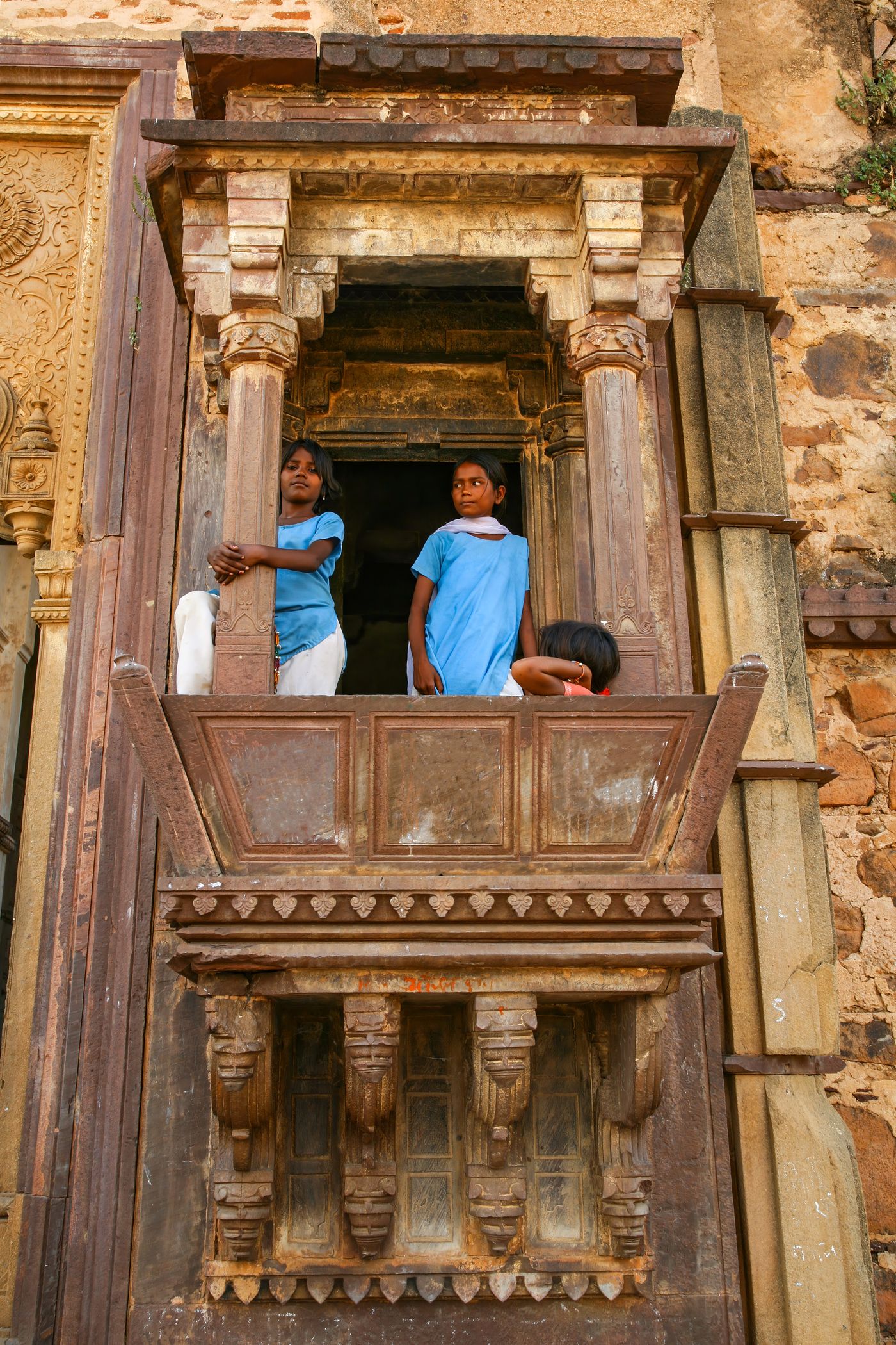 Local children peeping through a beautiful window of a historical Hindu temple in Orchha, India called Chaturbhuj 