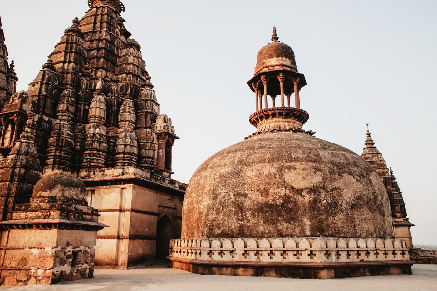 The gracefully aged cenotaphs and bas-reliefs on the roof of the temple in Orchha City looking over the complex 