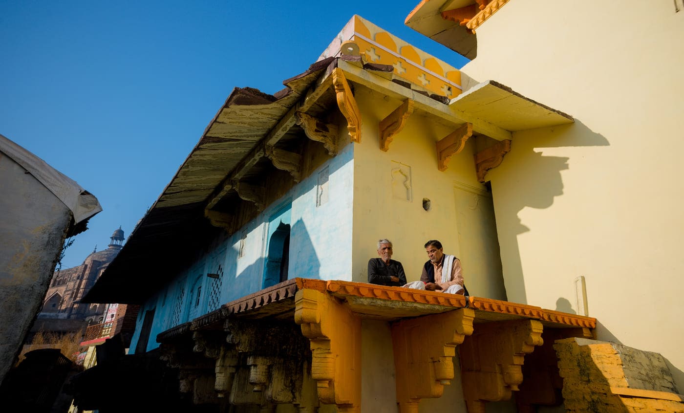 Two men sitting outside the house and soaking up the winter sunlight in Orchha 