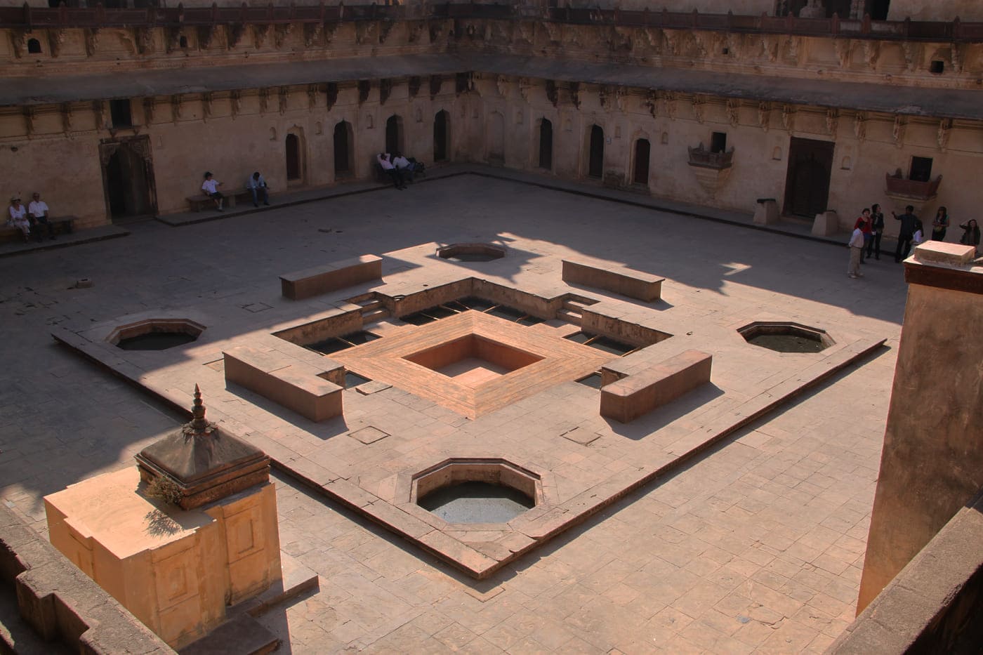 Visitors sit by the shade avoiding the harsh summer sun at the primary courtyard at the Jahangir Palace which was one amongst the many used to welcome guests, Orchha 