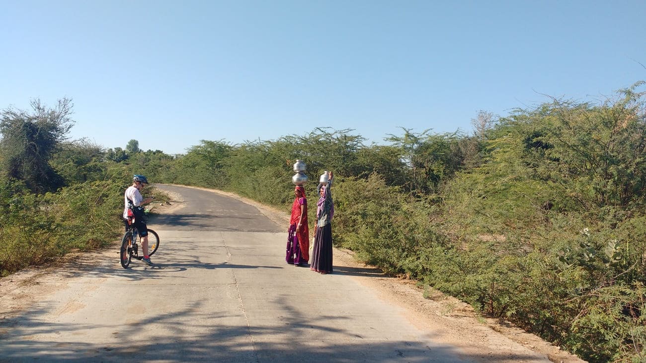 A beautiful photo opportunity of local women in colorful dress carrying silver pots on their heads