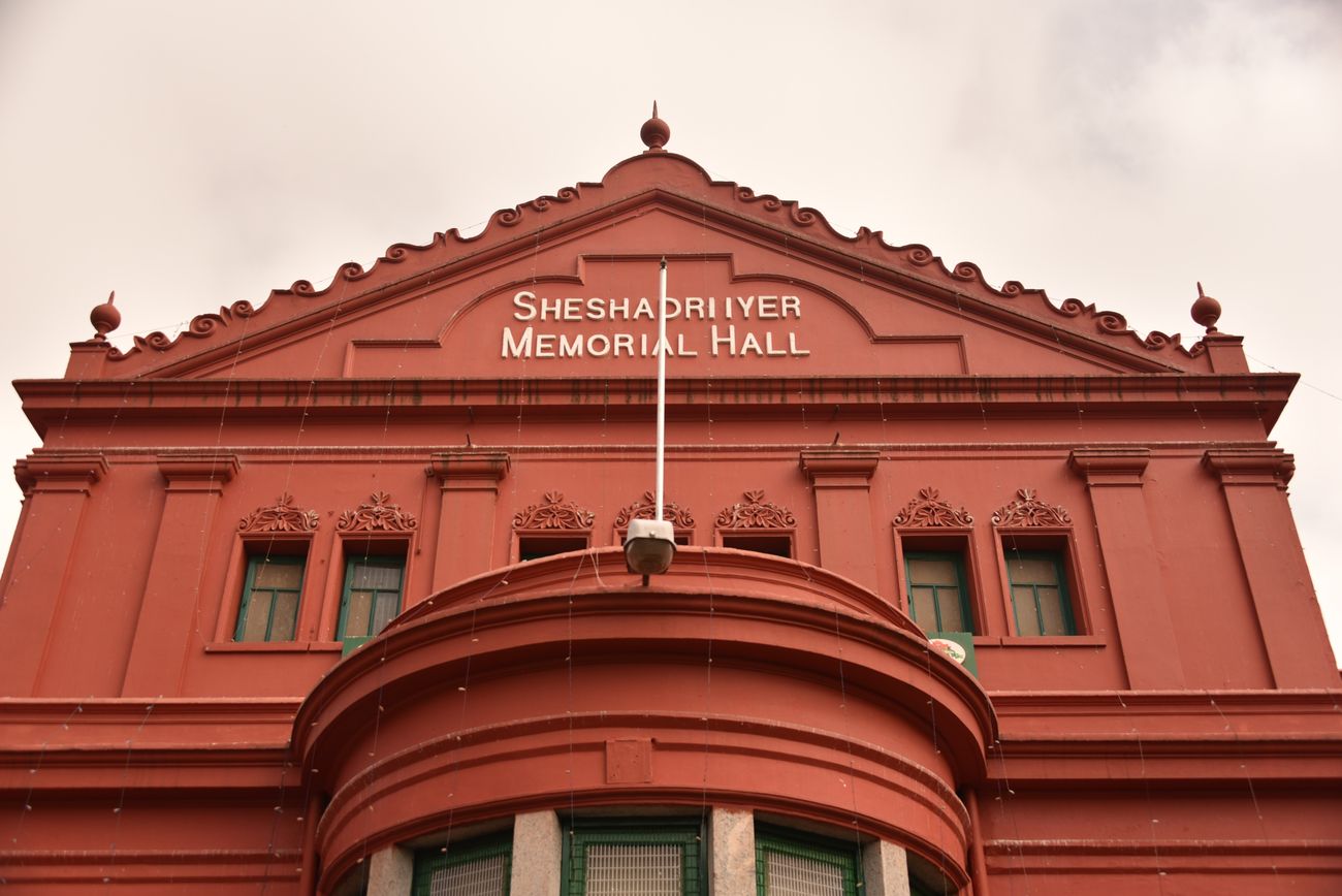 A majestic view of the State Central Library, known as Seshadri Iyer Memorial Hall which has a striking red building with a unique round room 