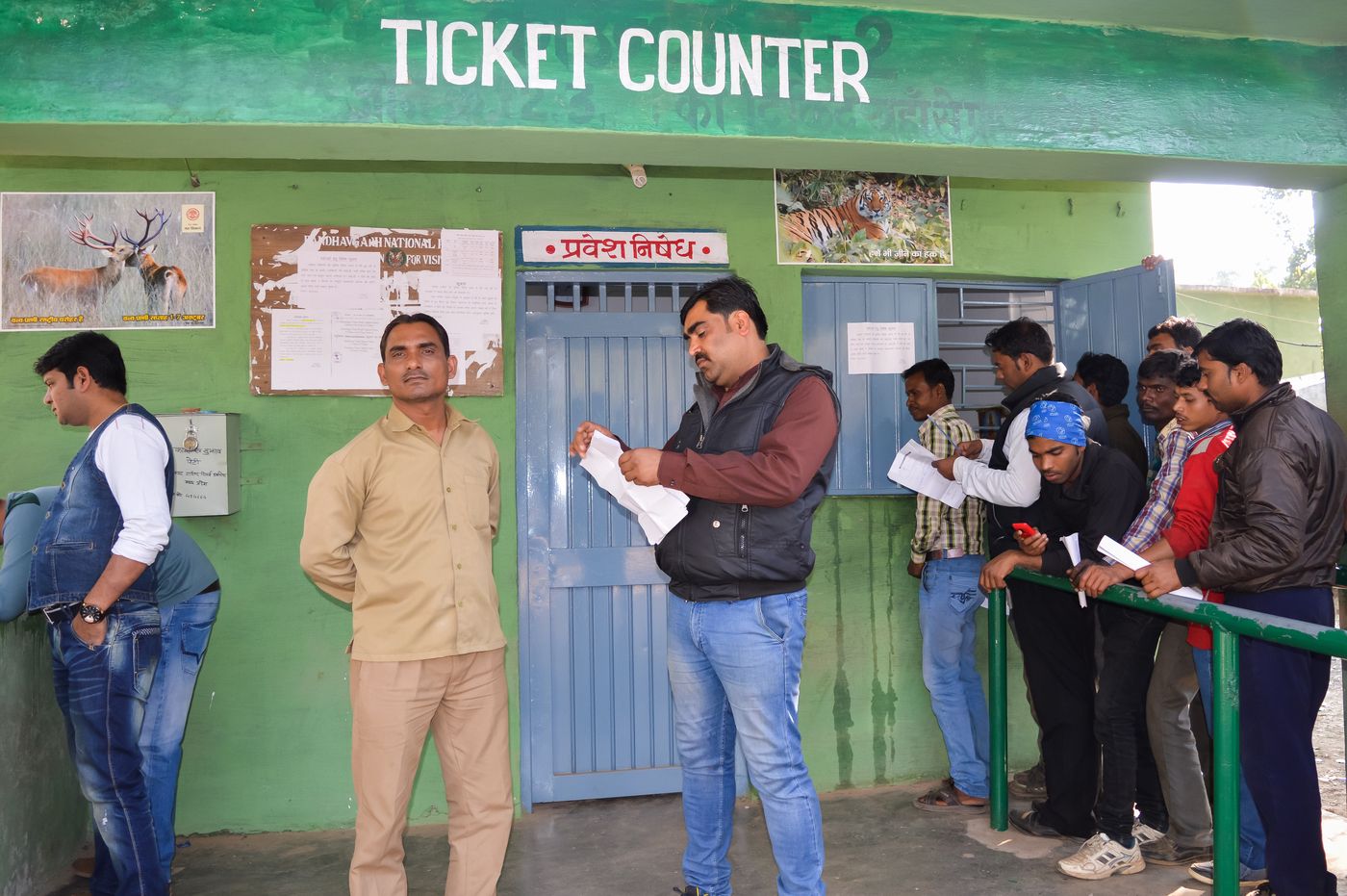 A naturalist checks his guests’ permits while other visitors stand in line at the ticket counter outside Bandhavgarh Reserve.