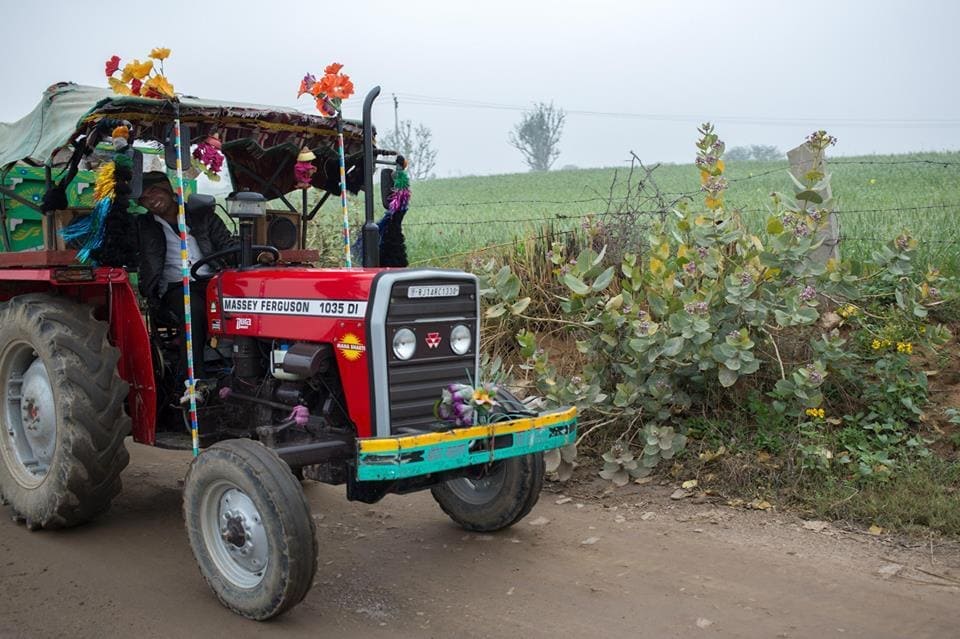 A tractor on a farm road near a village in Rajasthan