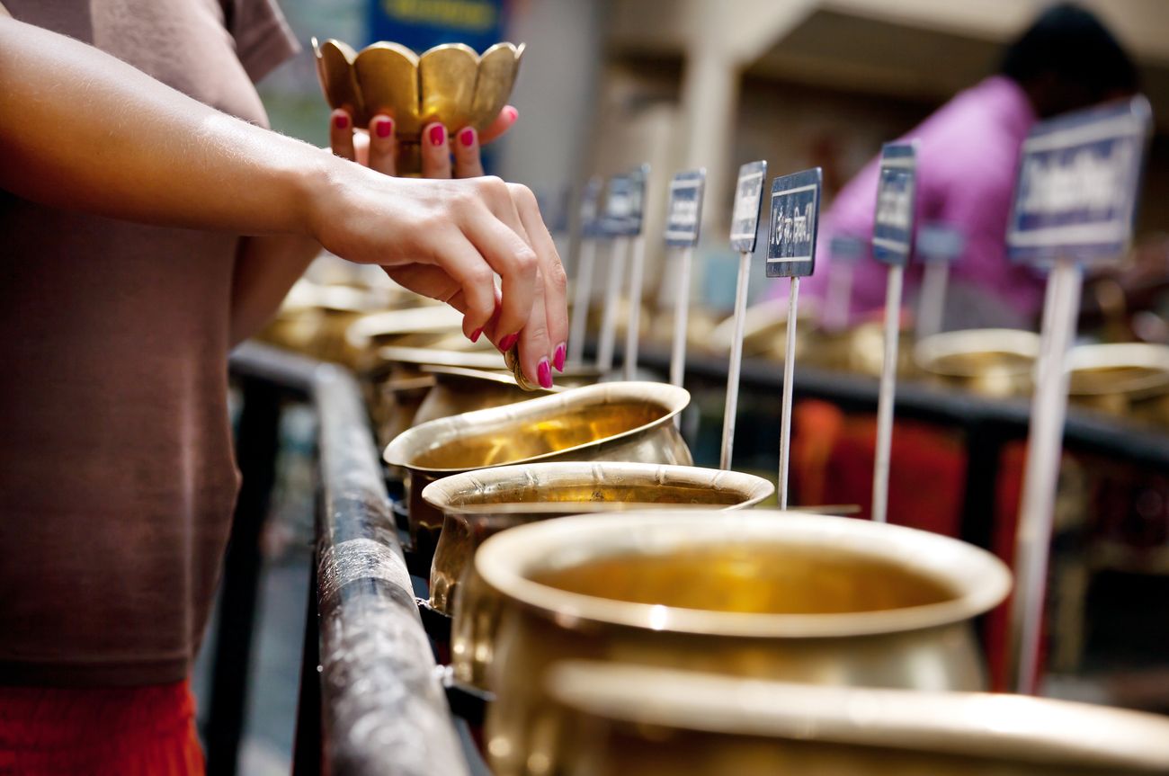 A woman with a bowl of 108 coins doing the ritual of worshiping Lord Shiva with the mantra Om Namah Shivaya at the Shiva temple