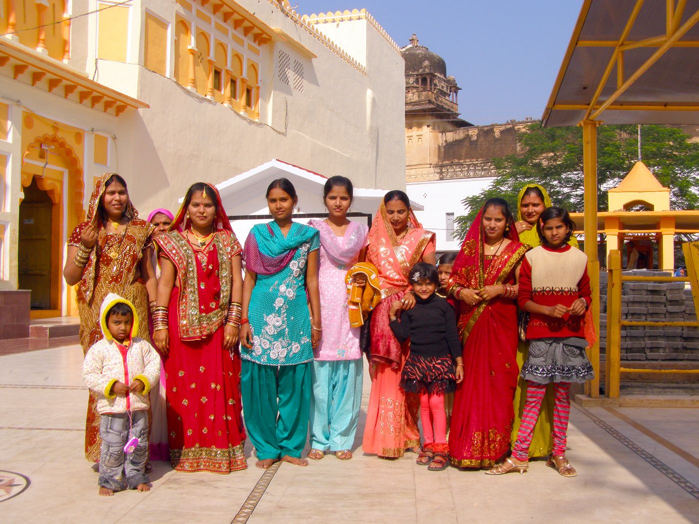 Against the backdrop of Ram Raja temple, some women in traditional Indian clothes take a picture. It is a holy Hindu pilgrimage site well-known as Orchha Temple 