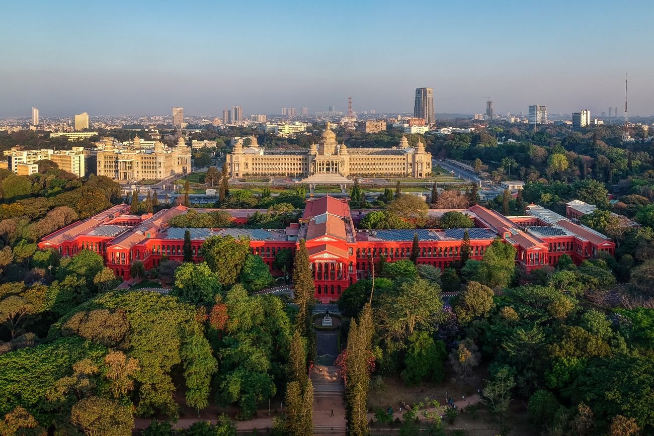 An aerial view of Vidhana Soudha and High Court building surrounded with lush green trees. Bangalore has been known by many epithets over the decades as Garden City, Pensioner's Paradise and Silicon Valley of India