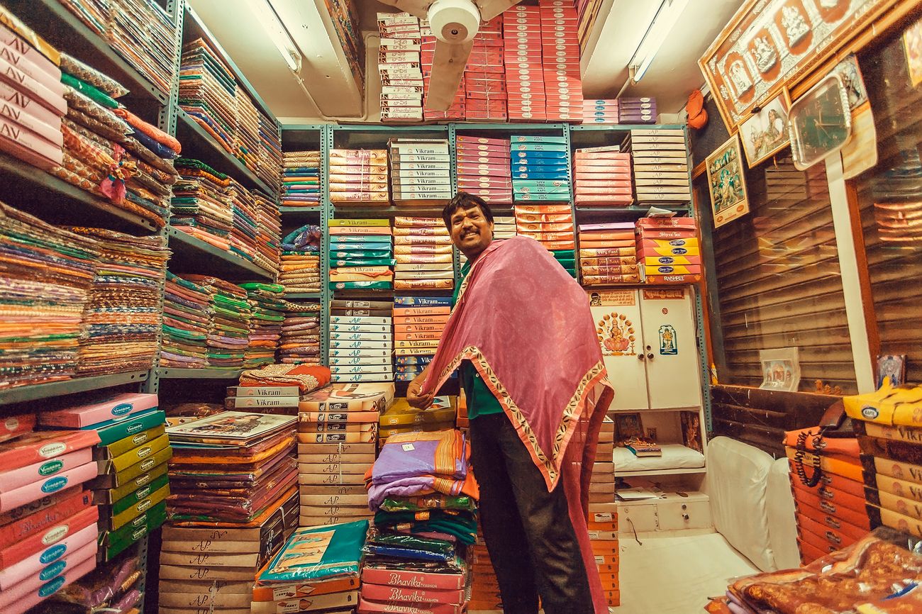 An Indian seller with textile joyfully waits for customers in traditional markets with a huge number of female clothing. The Silicon Valley of India, Bangalore is the third most populous Indian city with a population of 8.52 million