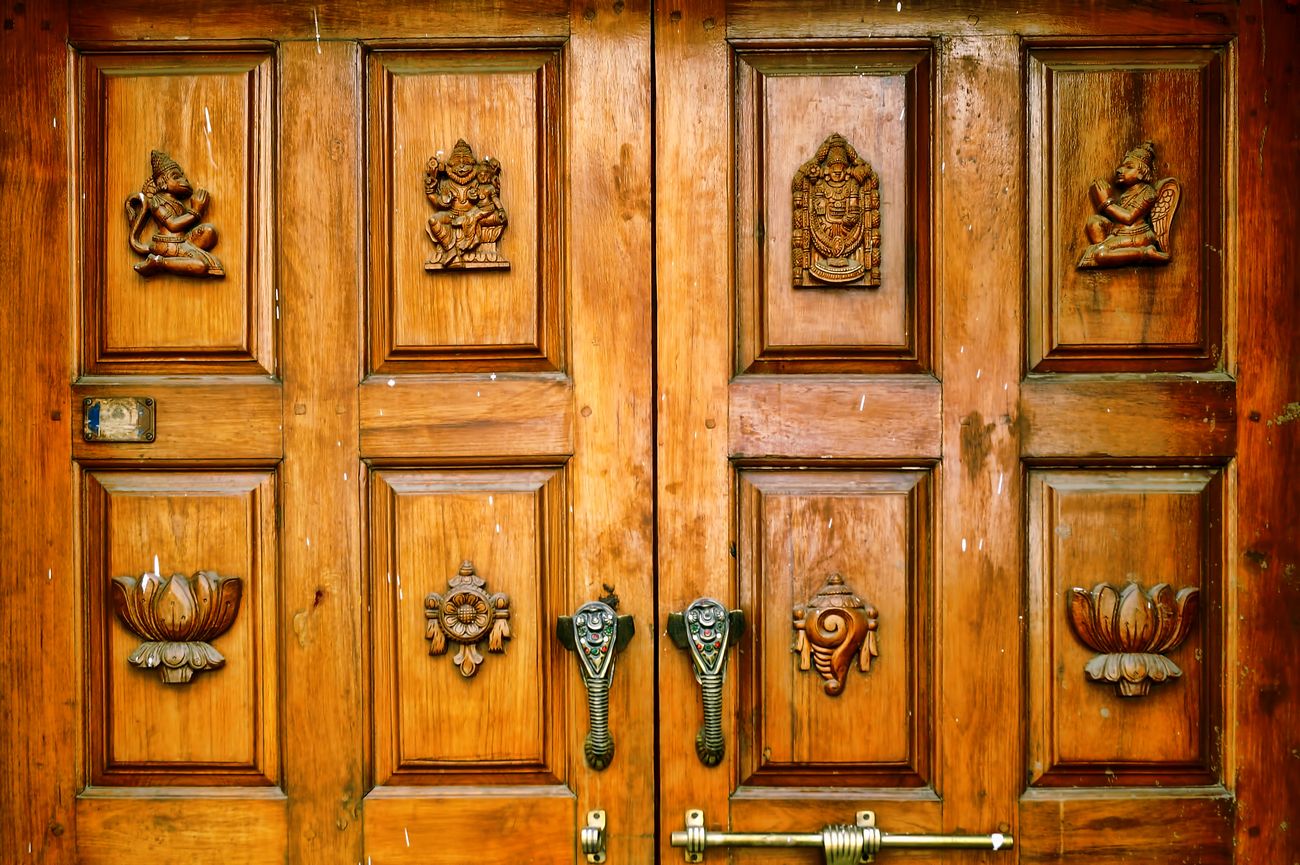 Intricate carvings of sacred religious Hindu symbols imprinted on the wooden door captured on the streets of Bangalore