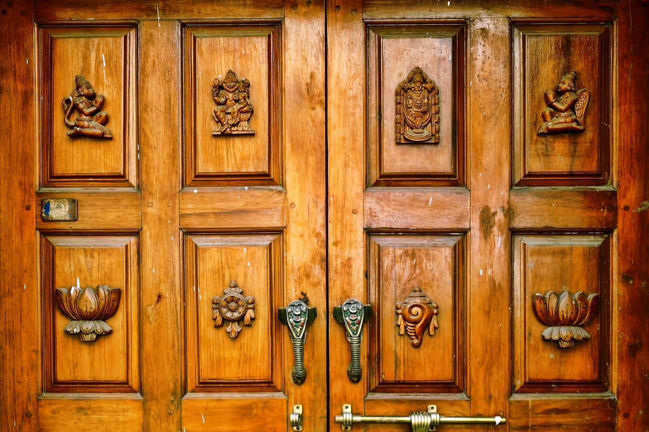 Intricate carvings of sacred religious Hindu symbols imprinted on the wooden door captured on the streets of Bangalore 