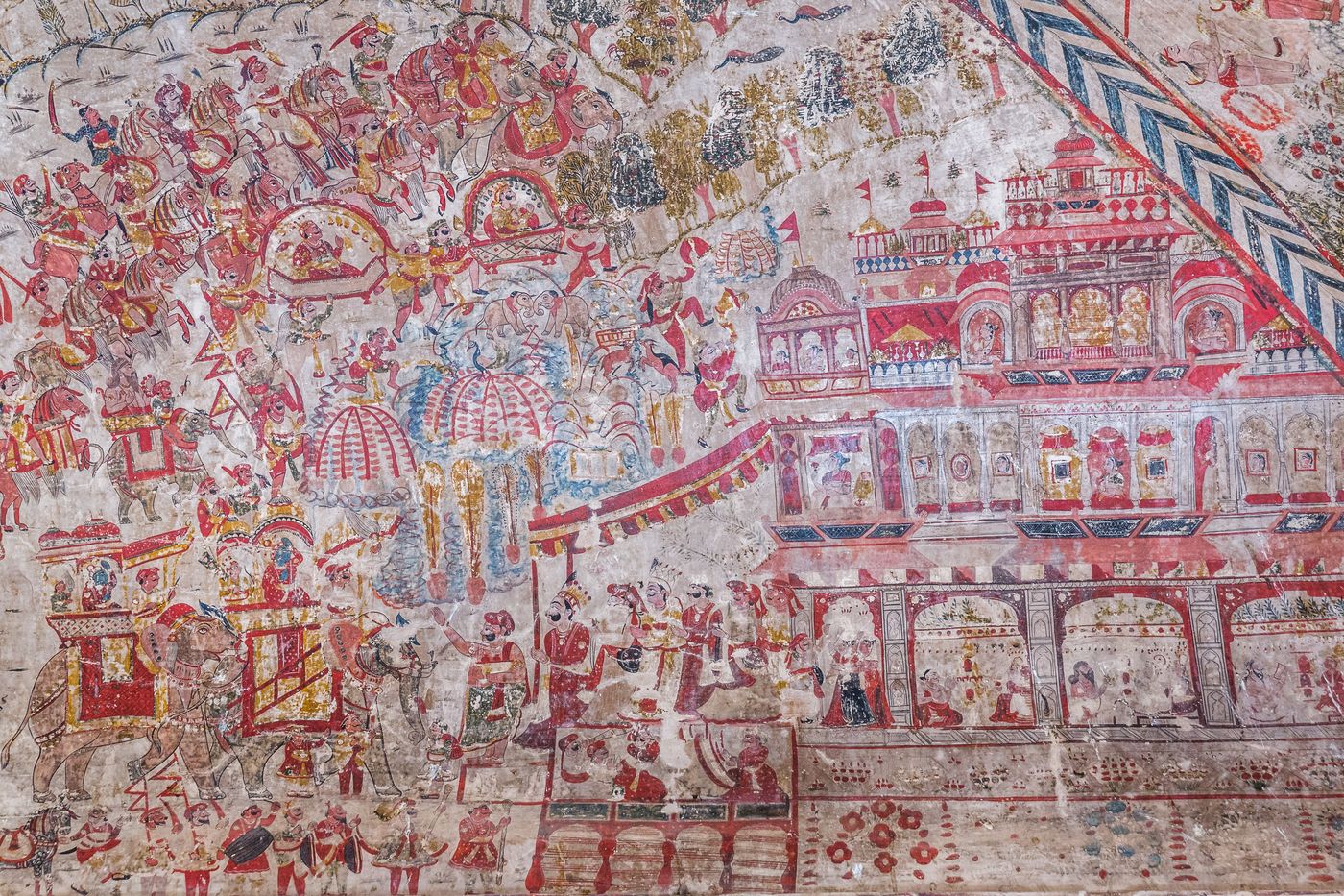 This painting shows how maharajas were welcomed back to their palaces after a victorious war. Ladies from the palace form a procession, the queens are watching from the windows, people play musical instruments, and sages perform Yajna, the fire worship, Orchha