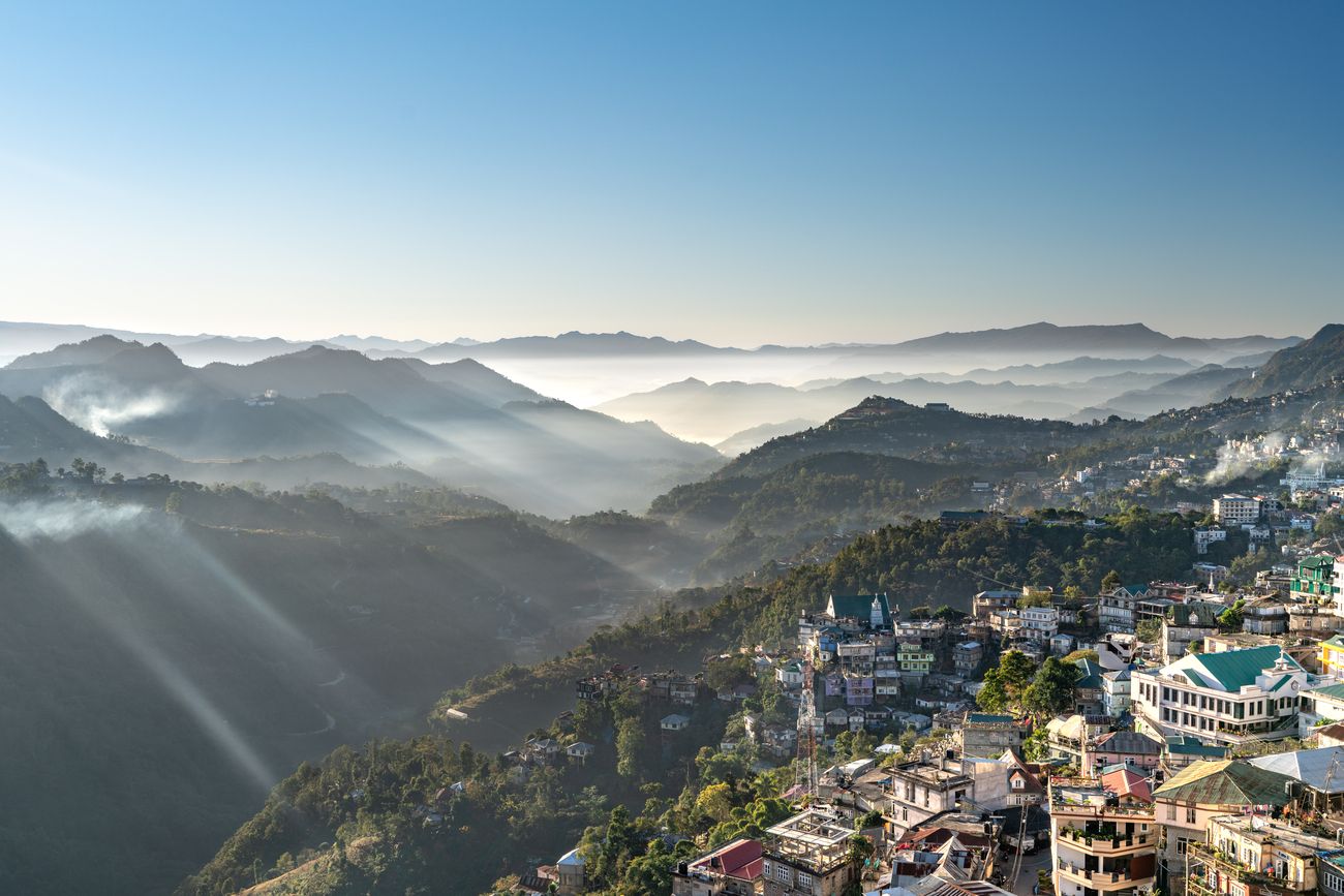 A bird’s eye view of the lovely city of Aizawl in Mizoram with mountains covered in mist, glistening in the light and reflecting sun rays as they reach the city