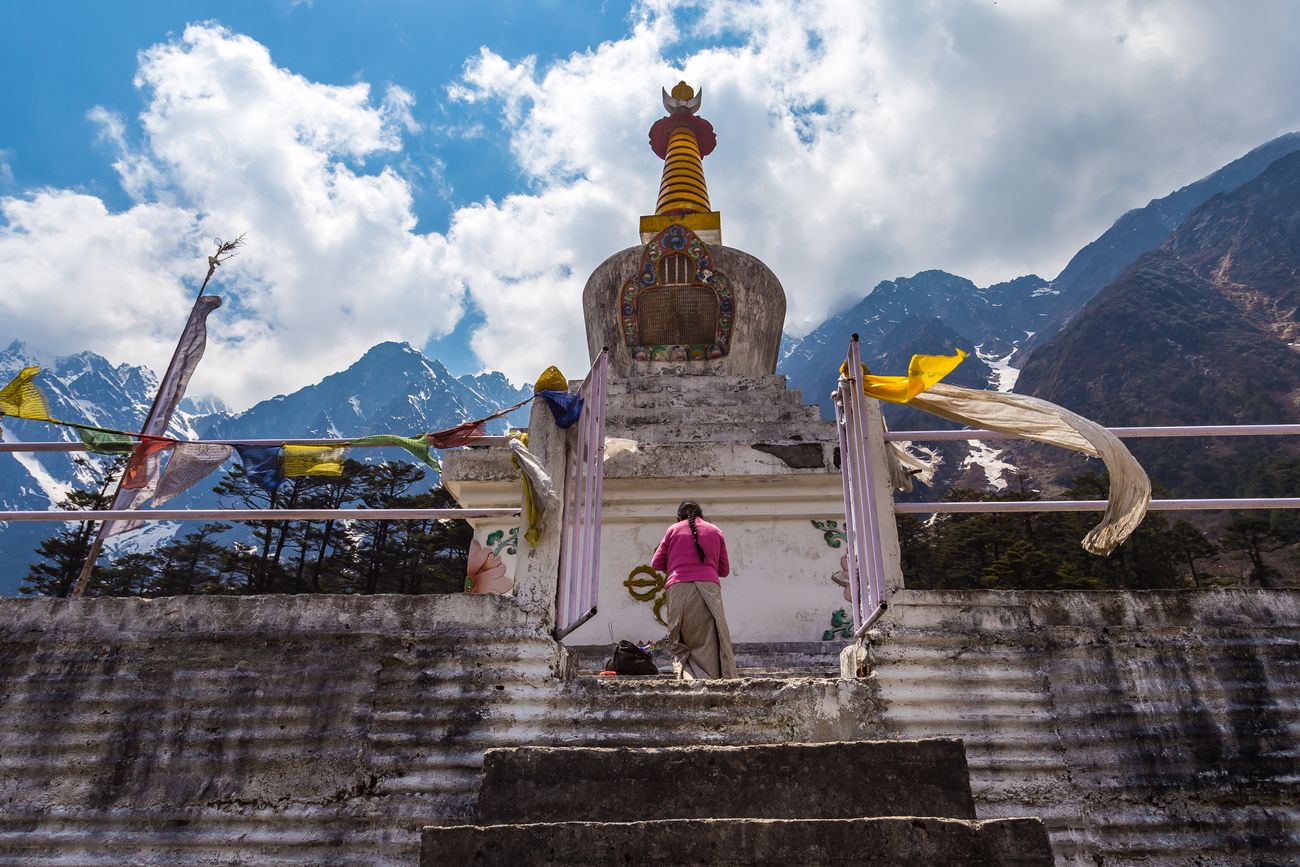 A devotee heads into the Lachung Stupa to offer her prayers as the wind blows the prayer flags in the Yumthang Valley