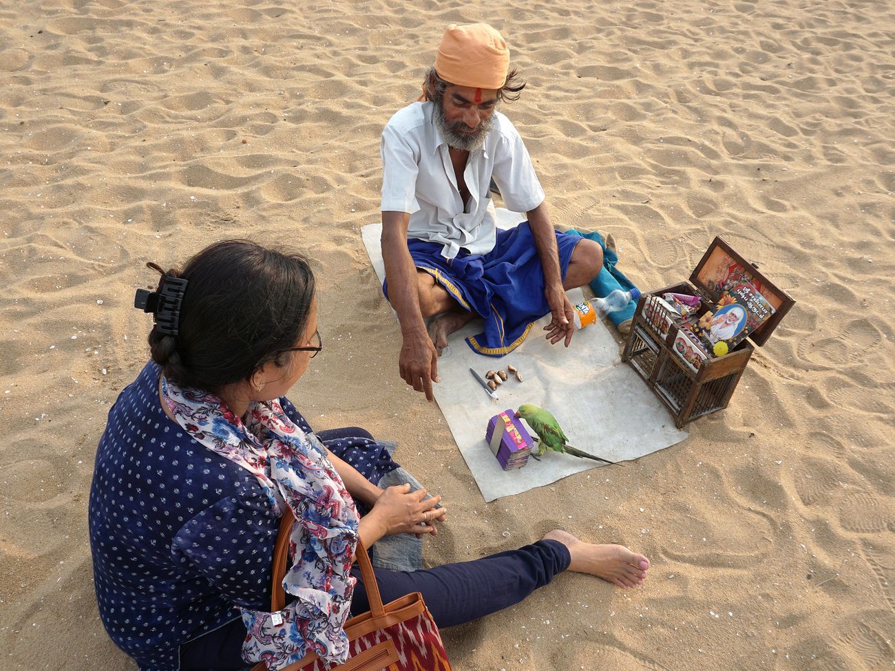 A lady is consulting a bird astrologer on Marina Beach. He will interpret the card his bird has picked