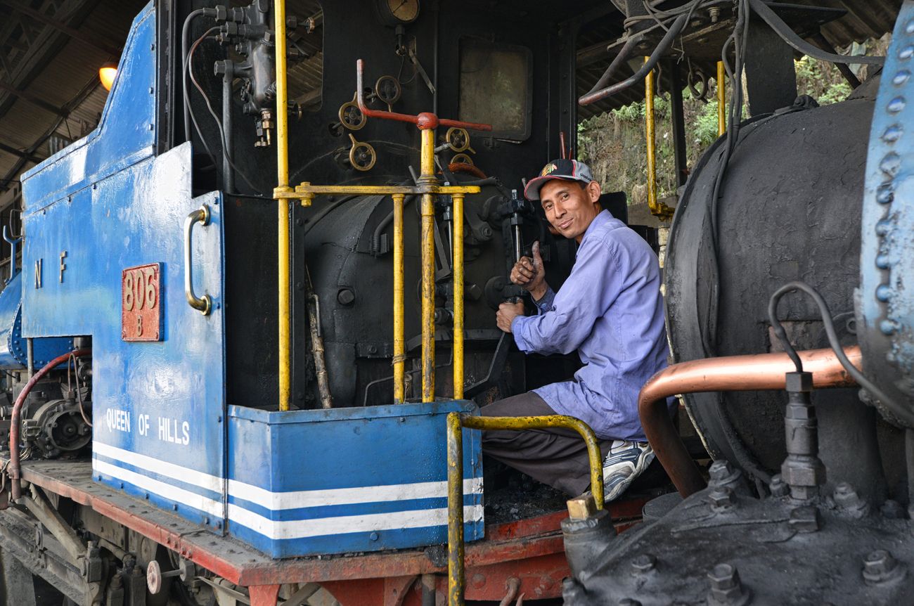 A mechanic checking the engine of the Darjeeling Himalayan Railway Train, lovingly referred to as the Toy Train, to ensure safety of passengers