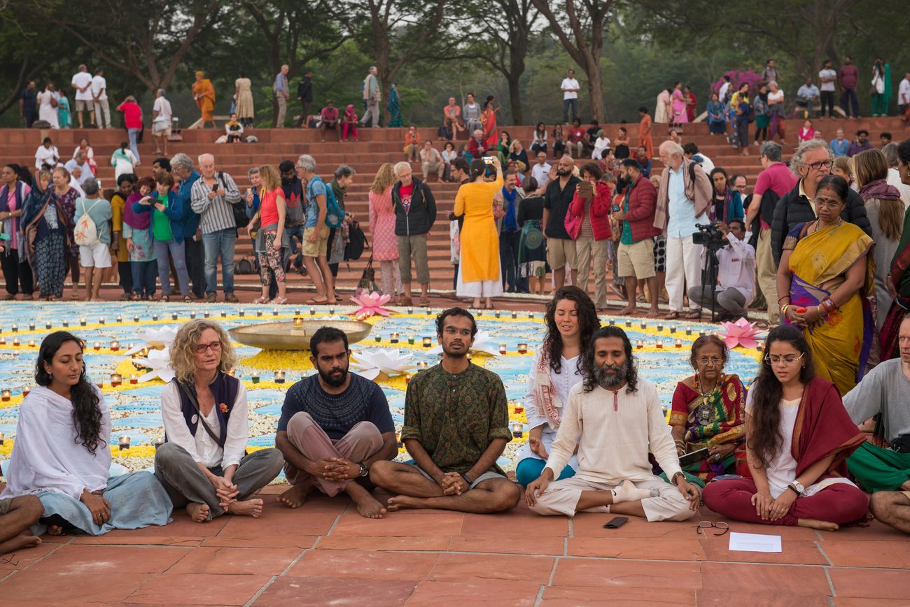 A meditation ceremony taking place at the Matrimandir Amphitheatre on the occasion of Auroville Birthday