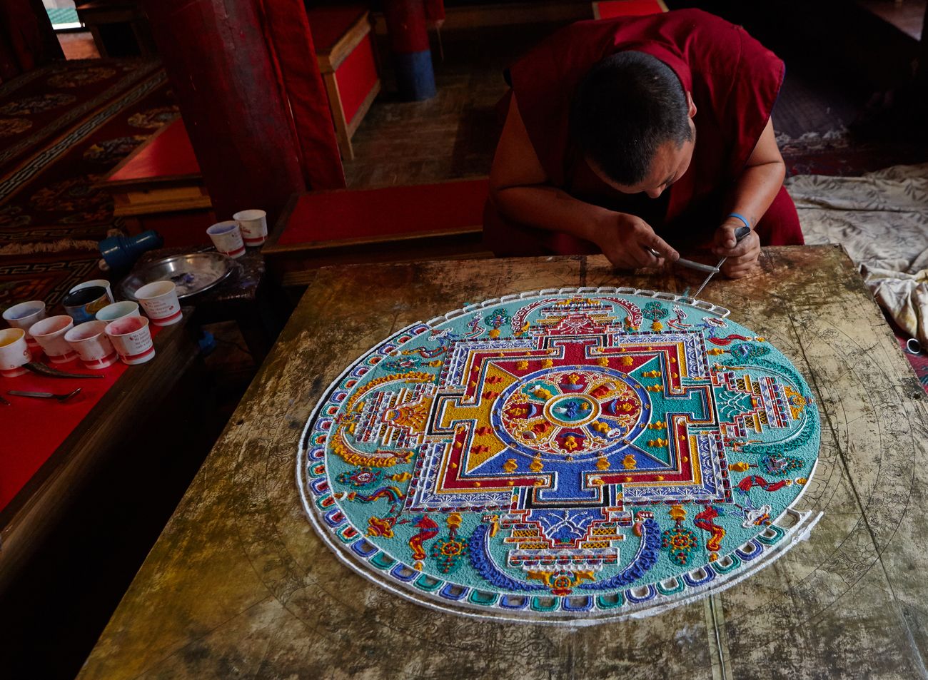A monk constructs an intricately patterned mandala with coloured sand which is believed to emit positive energy at a monastery in Tibet