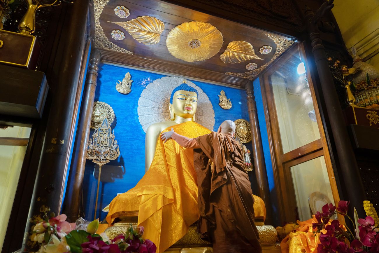 a monk worships the statue of buddha at mahabodhi temple