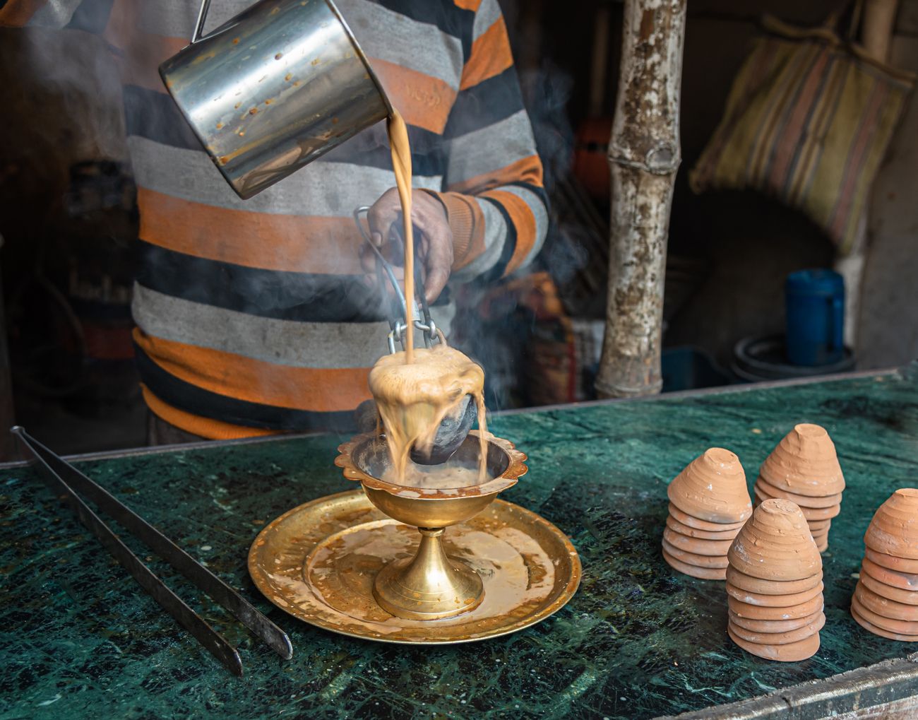 A roadside vendor in the process of preparing a mug of milk chai in a street in Kolkata 