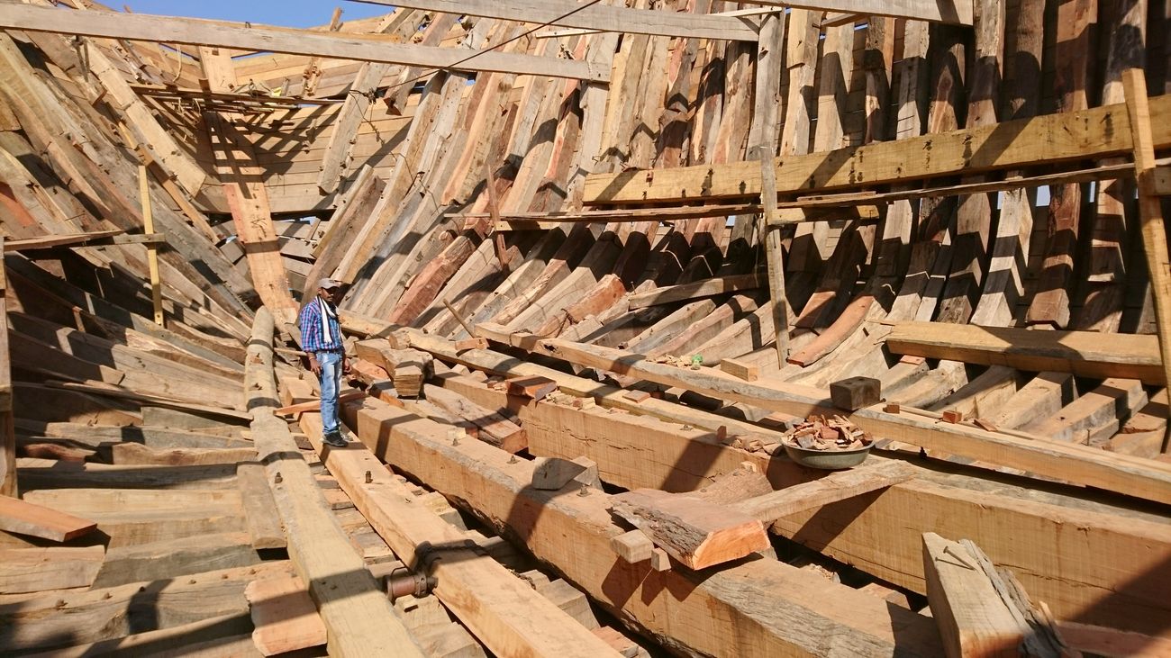 A shipmaker looks into the framework of a wooden boat under construction, traditionally these boats are known as Dhow in Gujarat 