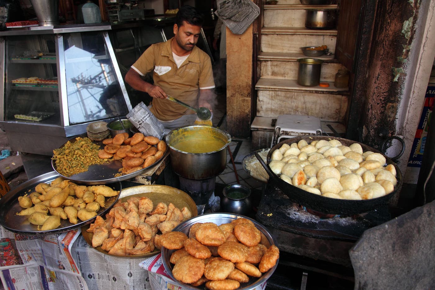 A street vendor busily preparing fried snacks like kachoris, pakodas, and samosas 