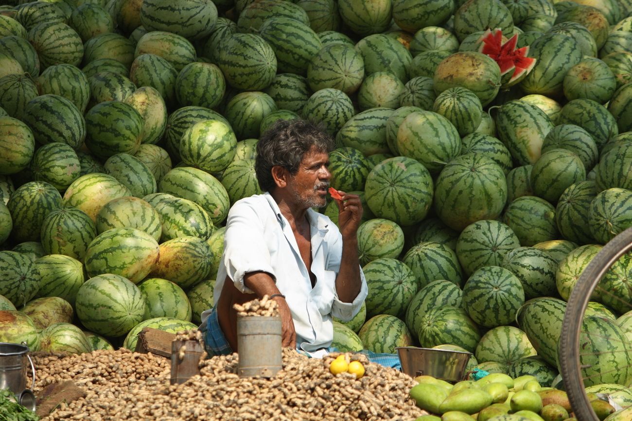 Sitting against a picture-perfect backdrop of green with a splash of red, a street vendor enjoys a slice of watermelon to relief the heat