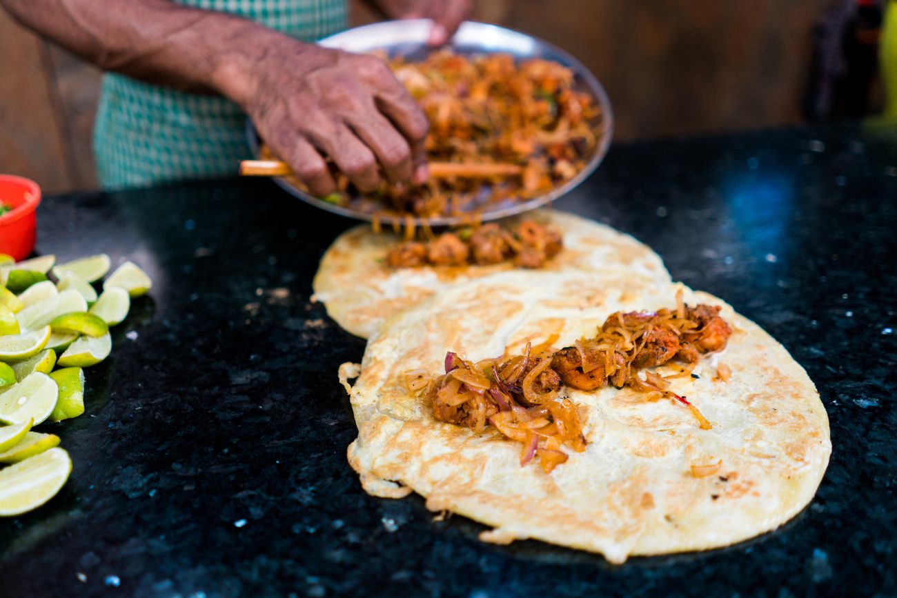 A street vendor prepare’s Kolkata's renowned Kathi Rolls with chicken and egg, ready to be hit with lime juice, onion, and other toppings