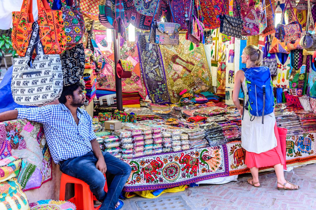 A tourist admiring colorful souvenirs from a traditional Indian shop at Dilli Haat, New Delhi