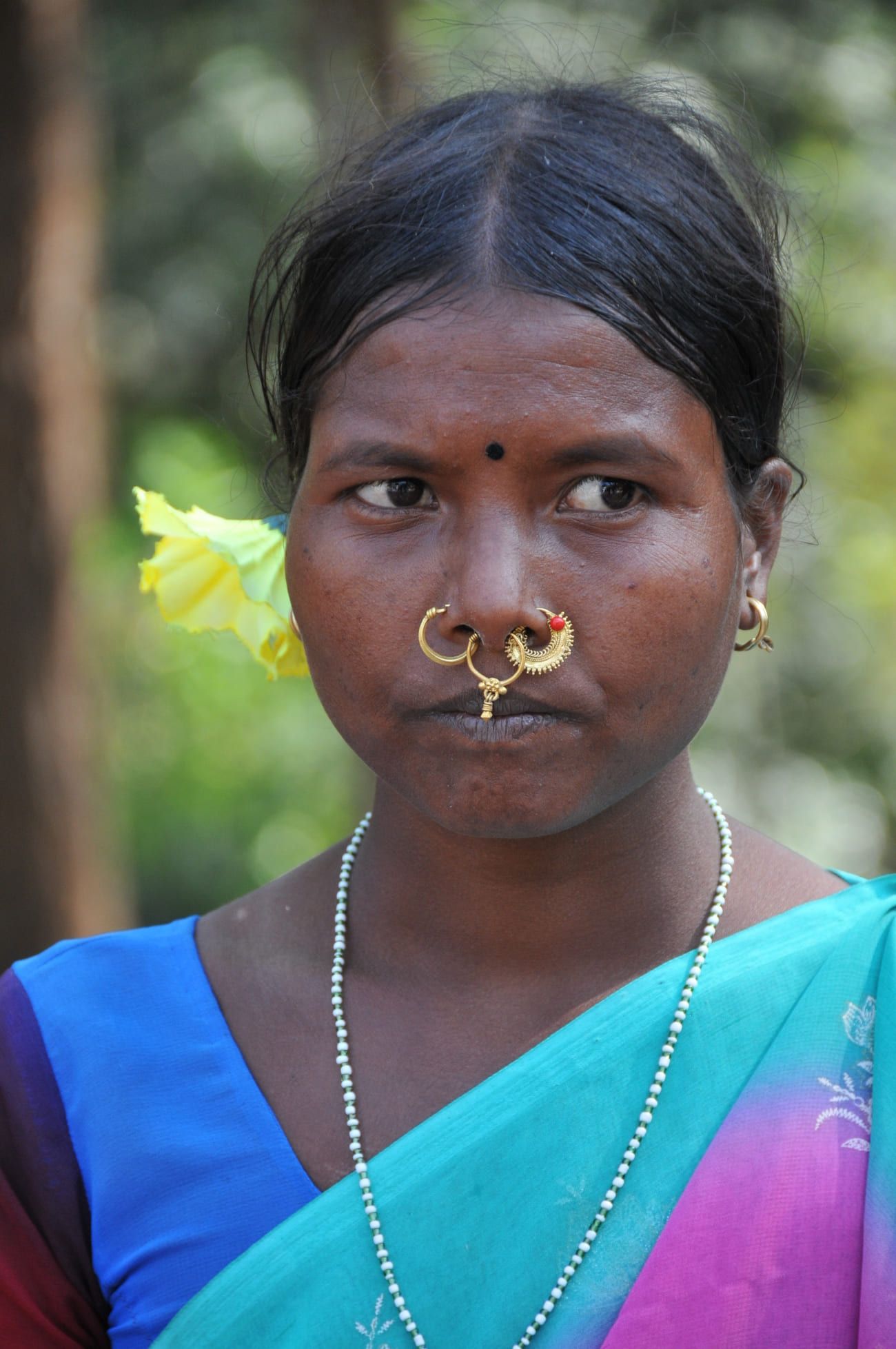 A tribal woman proudly wears her golden nose rings and a flower in her hair. Many different tribes live in this area 