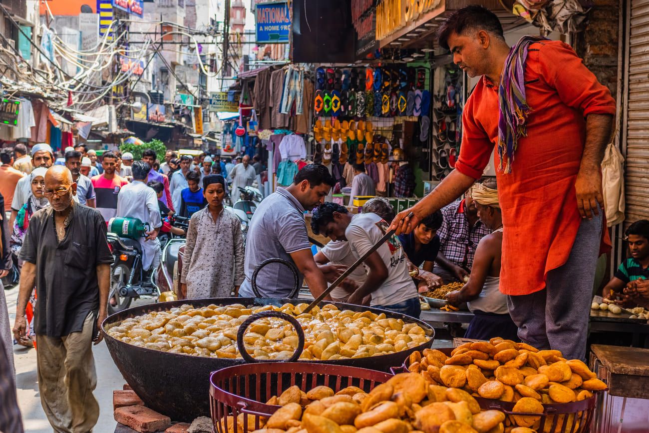 A vendor preparing snacks at a busy street market in Old Delhi