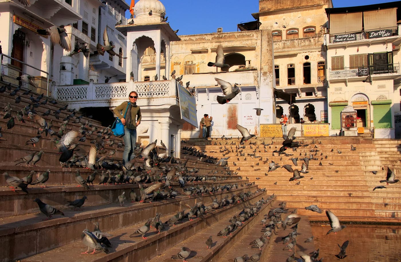 A visitor is having her picture taken amid a flock of birds on the steps of Pushkar’s holy lake 