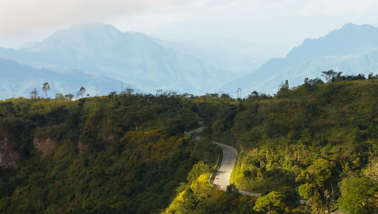 A walkway paved by constant use amidst the mountains covered in green grass, somewhere near the city of Lunglei in Mizoram