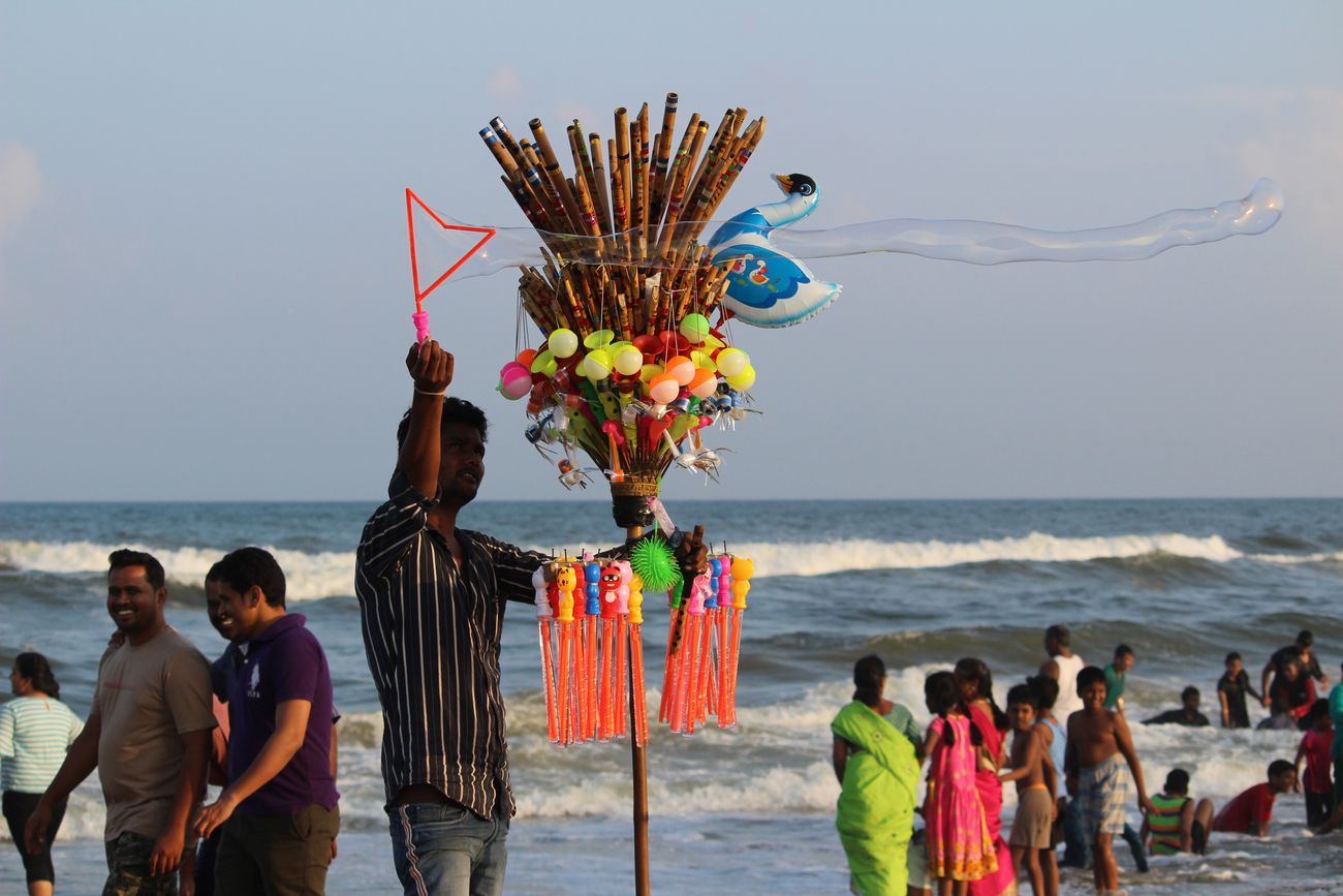 A young man, selling toys on the beach, tries to draw customers’ attention with soap bubbles