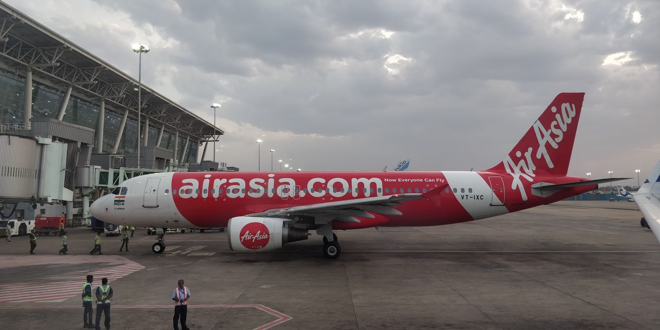 An Air Asia airplane, displaying its website in bold red, stands ready to welcome boarding passengers