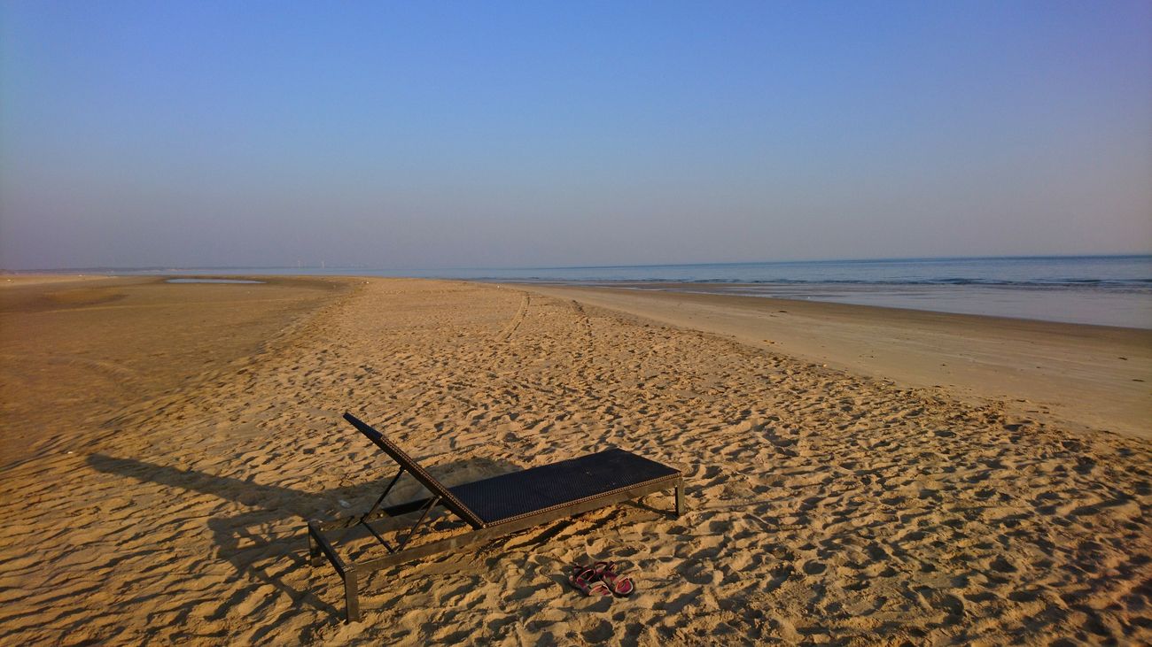 An inviting beach chair sits in the sands of the Mandvi beach of Gujarat, looking over the blue horizon 