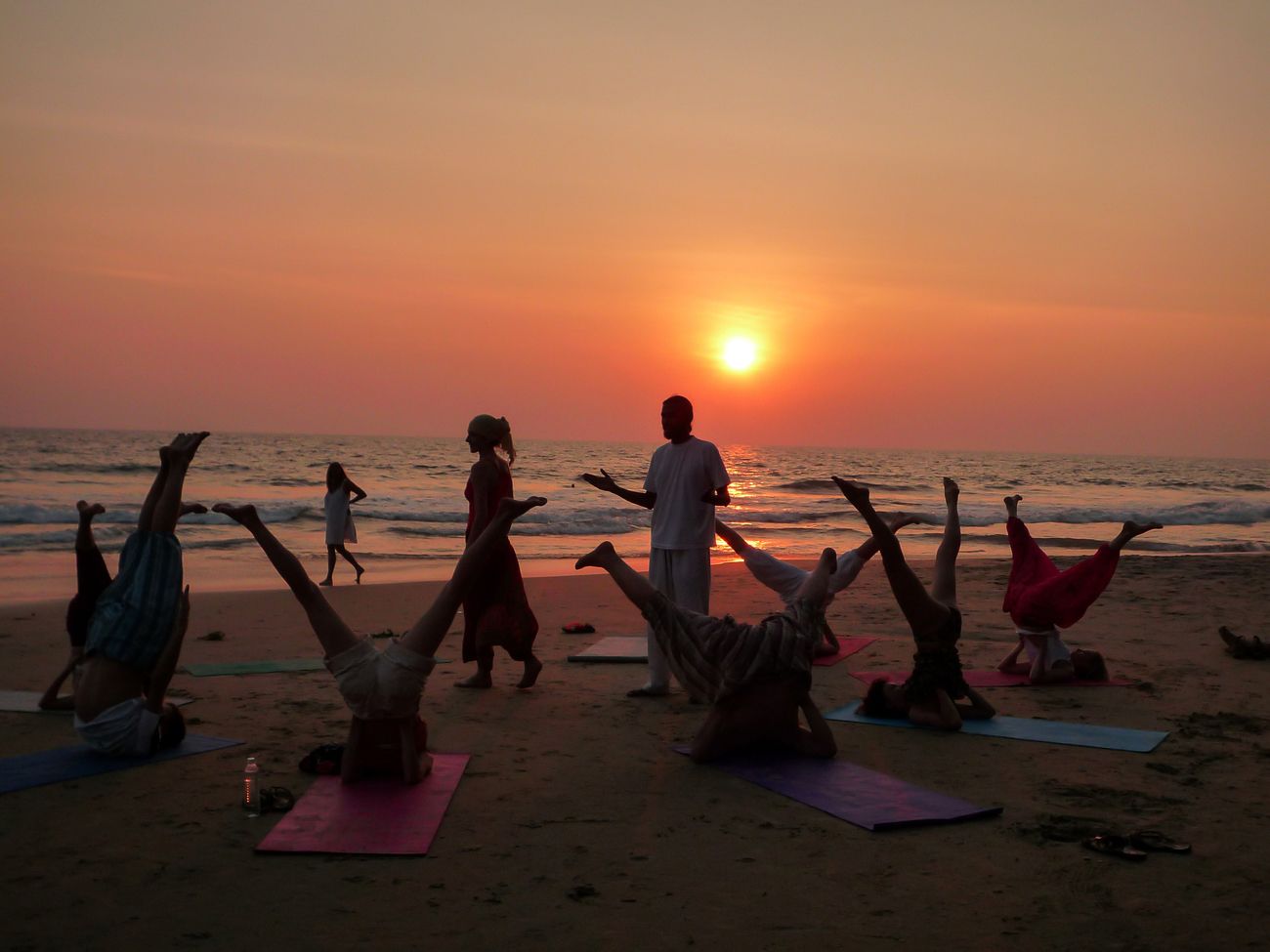 As the sun sets into the ocean, it casts a silhouette on the yogis at the dawn-time class by the beach in Kerala. © lightlook