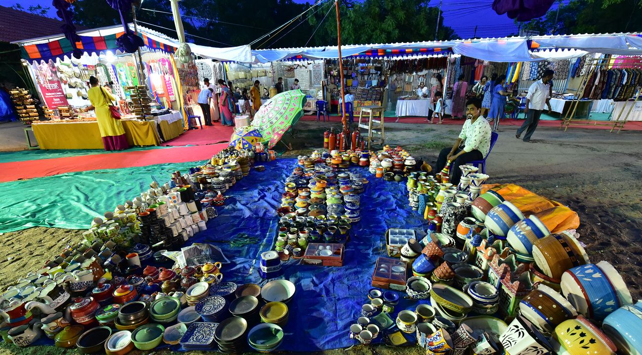 At a late evening open-air sale, a man waits patiently for customers to buy his ceramic ware