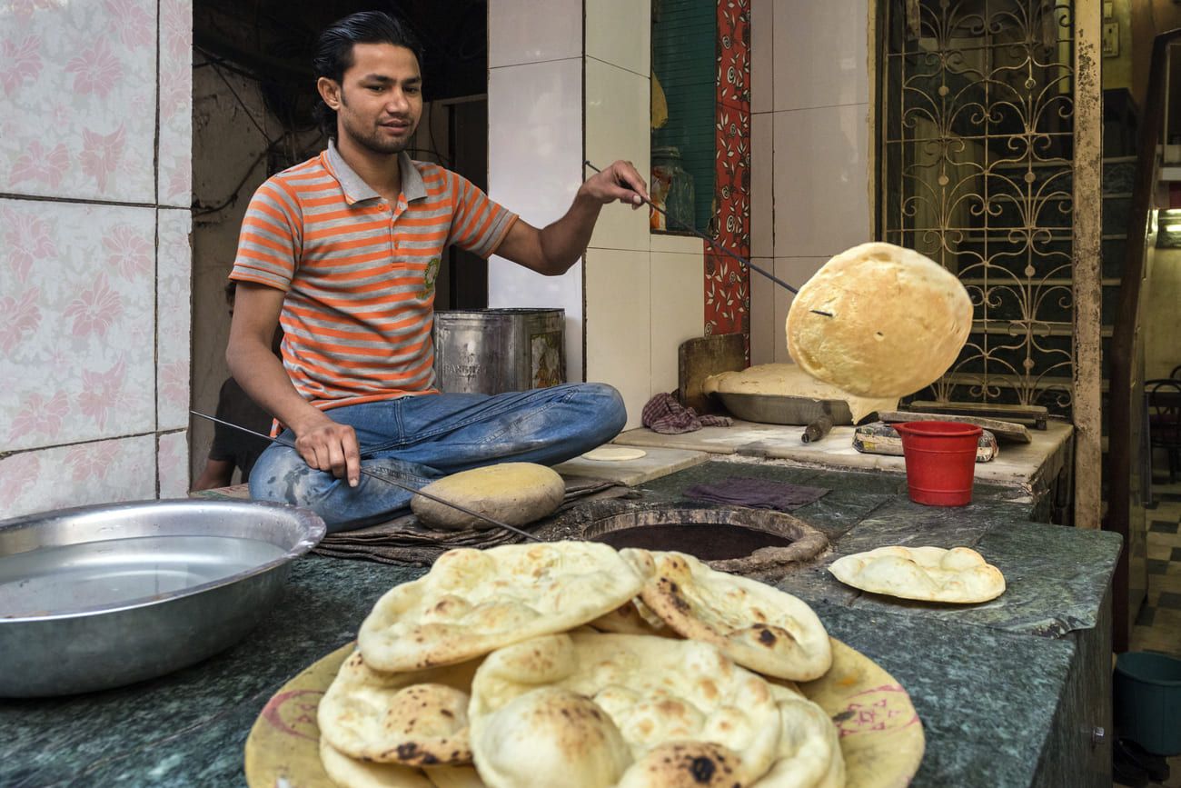 Baker baking naan in an outdoor oven in Delhi 