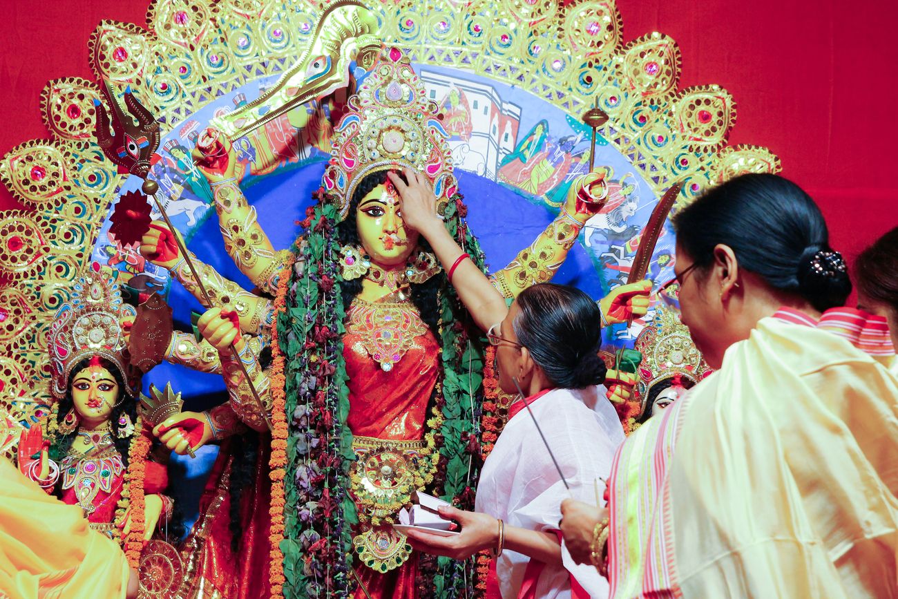 Bengali women welcome the idol of Goddess Durga with betel leaves and sweets 