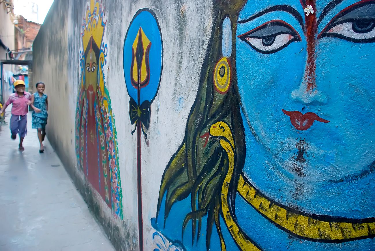 Children playing in a street in Kolkata with Murals of Shiva and other Indian Gods 