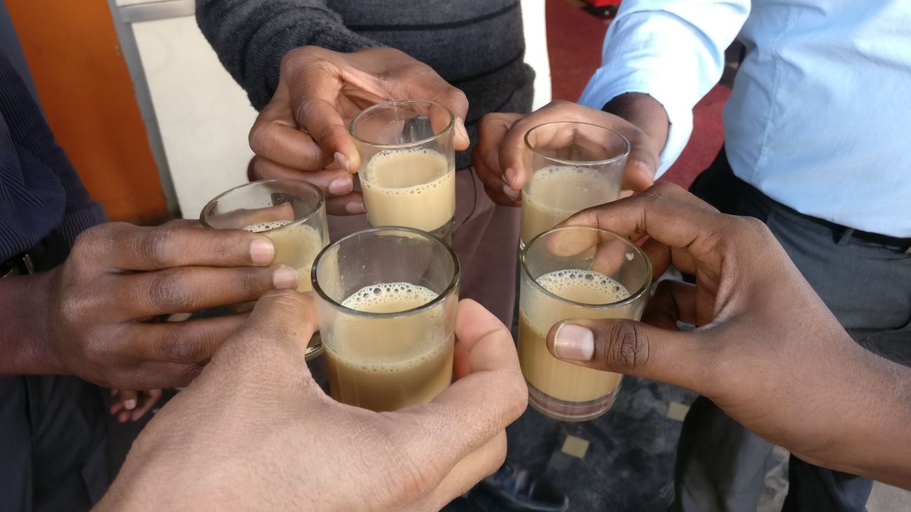 An intimate glimpse of a group of friends saluting each other with a glass of tea