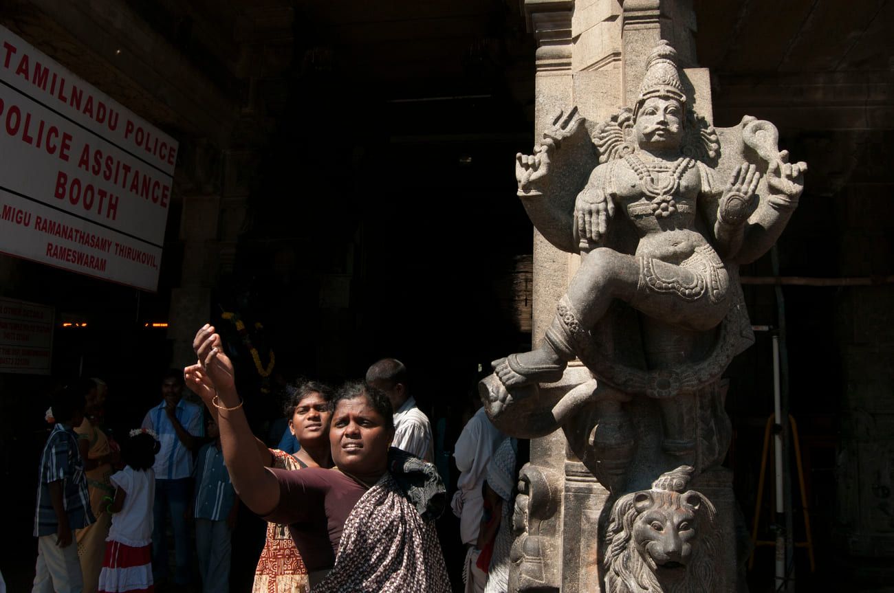 Hindu pilgrims walk past an exquisitely decorated pillar in a corridor of Ramanathaswamy Temple 
