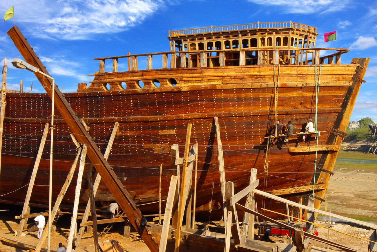 shipbuilders at work building a giant wooden floater at the mandvi beach