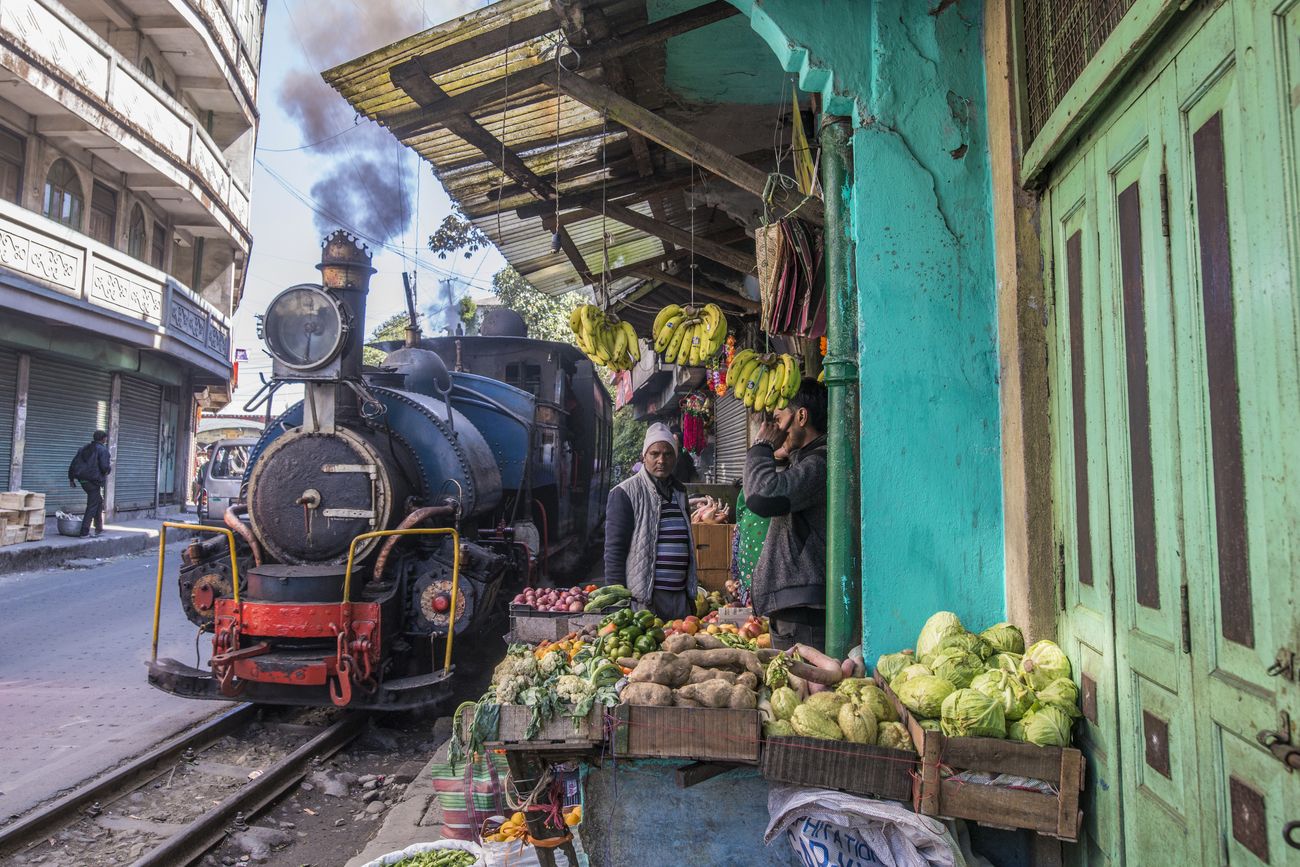 A rare sight, the Darjeeling Toy Train passing by a market stand near Ghum railways station with no more than a few inches clearance 