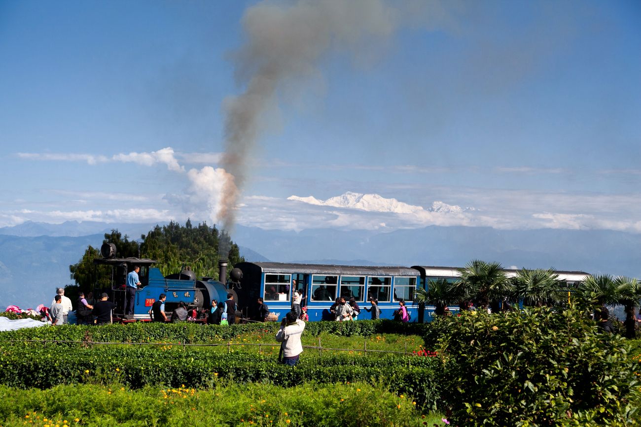 The UNESCO renowned Darjeeling Toy Train of the Indian Railway network passing through the lush fields with Mount Kanchenjunga in the background through the Batasia loop 