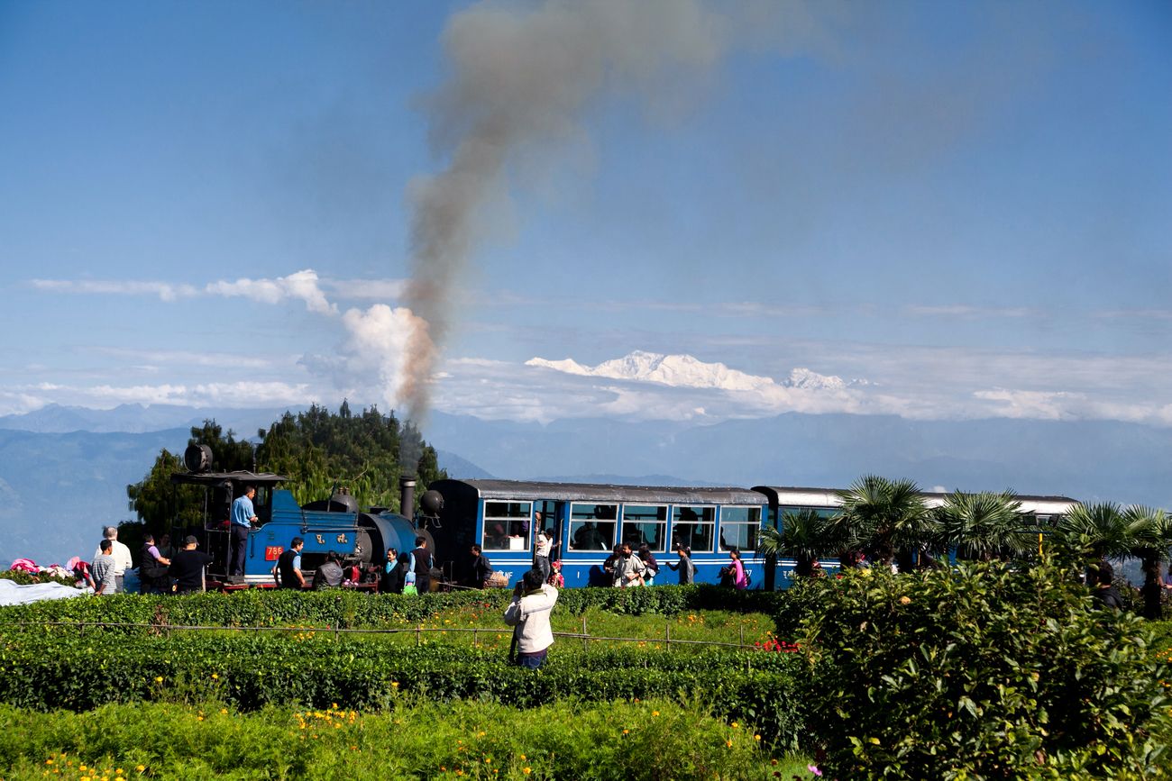 The UNESCO renowned Darjeeling Toy Train of the Indian Railway network passing through the lush fields with Mount Kanchenjunga in the background through the Batasia loop